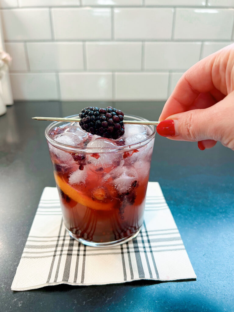 garnishing the drink with a blackberry